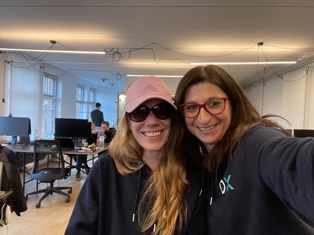 Colleagues smiling at the office in a casual, friendly setting.