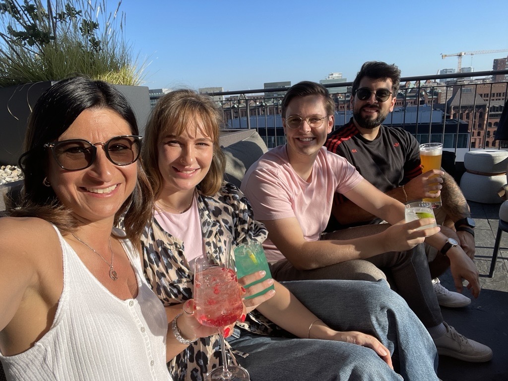 Team members enjoying rooftop drinks together on a sunny day.
