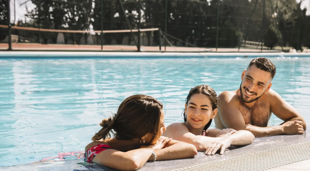 A family happily resting against the side of a pool